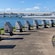 A walkway with stone sculptures featuring informative plaques overlooking the water and the Battleship Missouri submarine